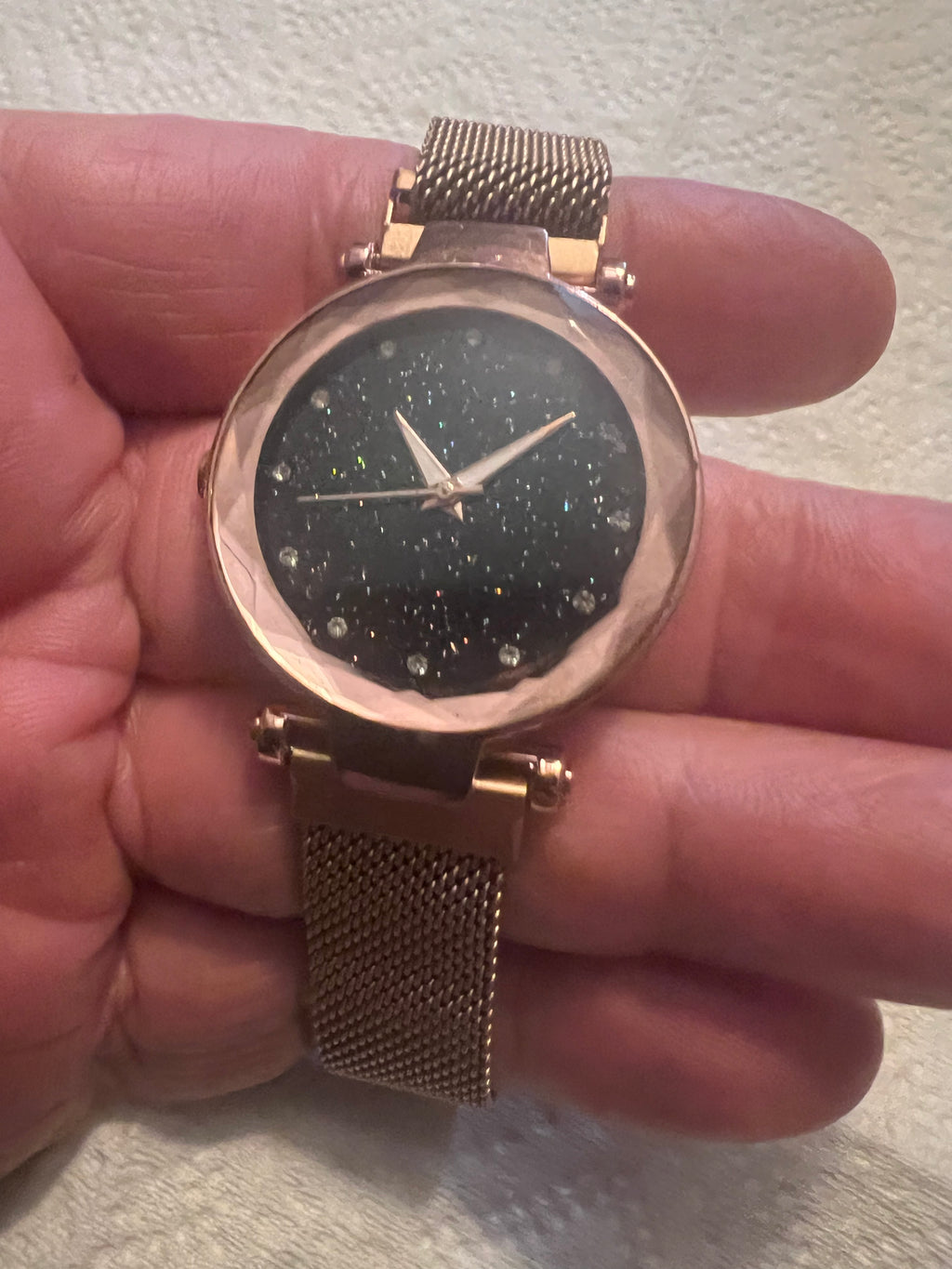 women's rose gold-toned quartz watch featuring a black "starry sky" glitter dial and a magnetic mesh strap.